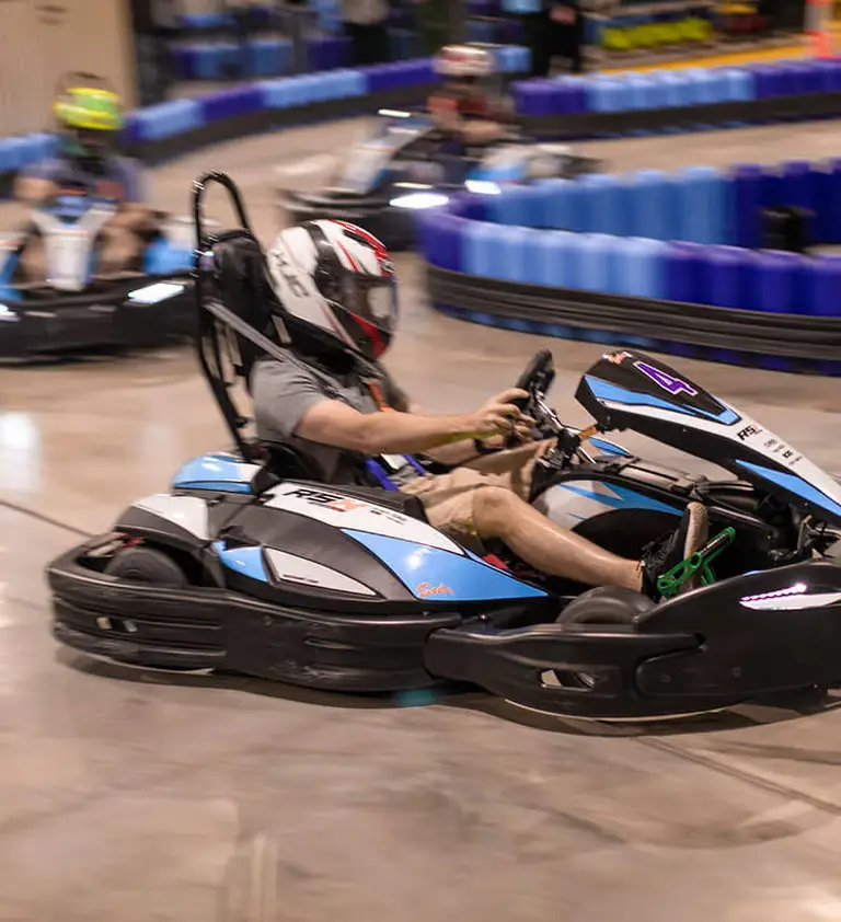 A helmeted racer driving a PowerPlay electric kart